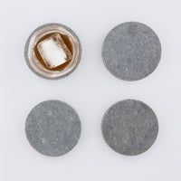 4 round marble like coasters in Caesarstone 4033 Rugged Concrete. Shown with whiskey glass and large ice cube.