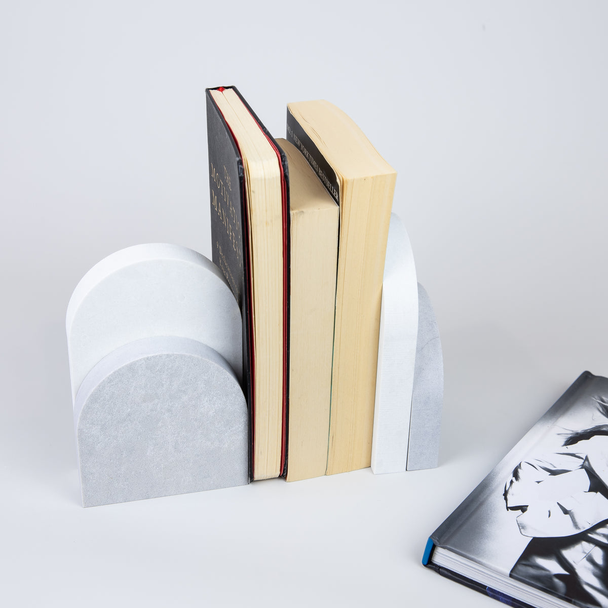 Quartz Bookend Set is 4cm thick. Styled with books. Available in Airy Concrete partnered with Organic White by Caesarstone the feel of concrete in full movement, meets a clean white surface with subtly blended undertones, reflecting a natural appearance that is effortlessly chic. The perfect addition to your home decor, similar to marble bookends.