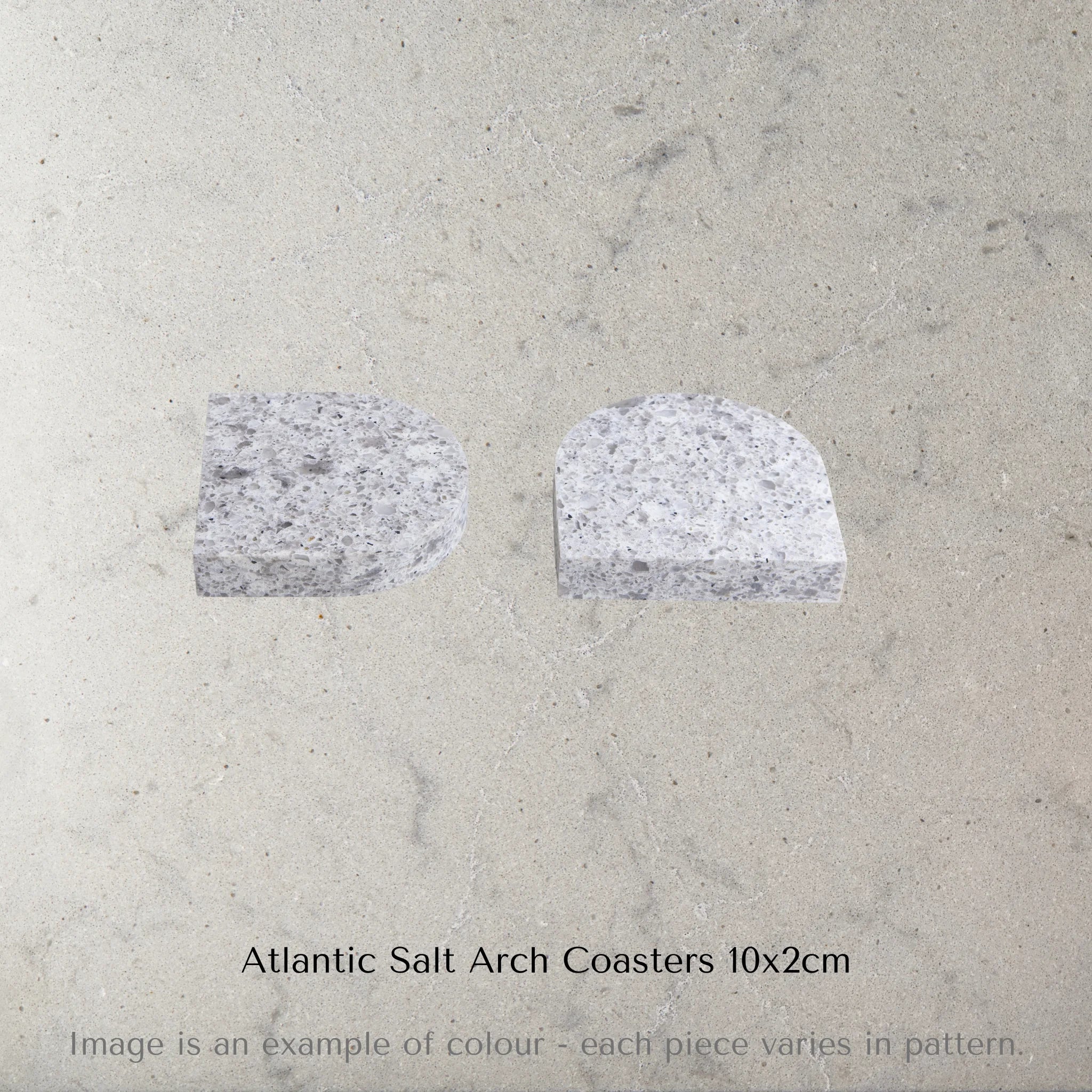 Two Caesarstone Atlantic Salt Arch Coasters on a concrete surface with text 'Atlantic Salt Arch Coasters 10x2cm'.