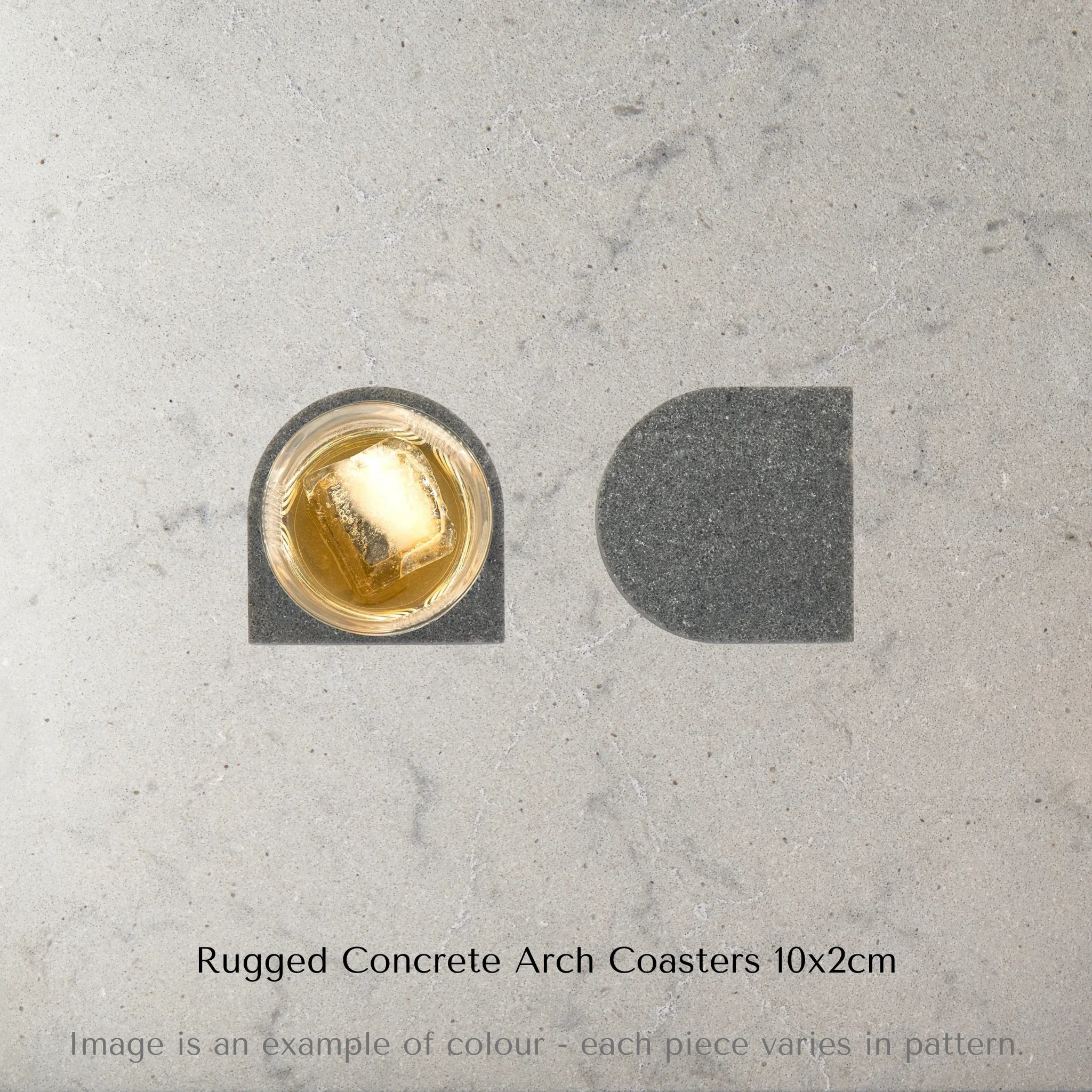 Arial image of Caesarstone rugged concrete arch coaster with a glass of whiskey and large ice cube on a marble surface with text 'Rugged Concrete Arch Coasters 10x2cm'.