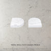 Two Caesarstone White Attica Arch Coasters on a grey marble surface with text 'White Attica Arch Coasters 10x2cm'.