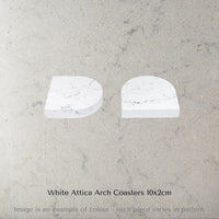 Two Caesarstone White Attica Arch Coasters on a grey marble surface with text 'White Attica Arch Coasters 10x2cm'.