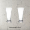 Two Dstill unbreakable pilsner beer glasses on a grey marble concrete background with text 'Unbreakable Beer Glasses'.