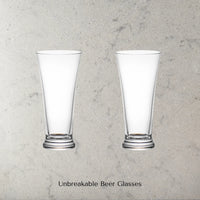 Two Dstill unbreakable pilsner beer glasses on a grey marble concrete background with text 'Unbreakable Beer Glasses'.