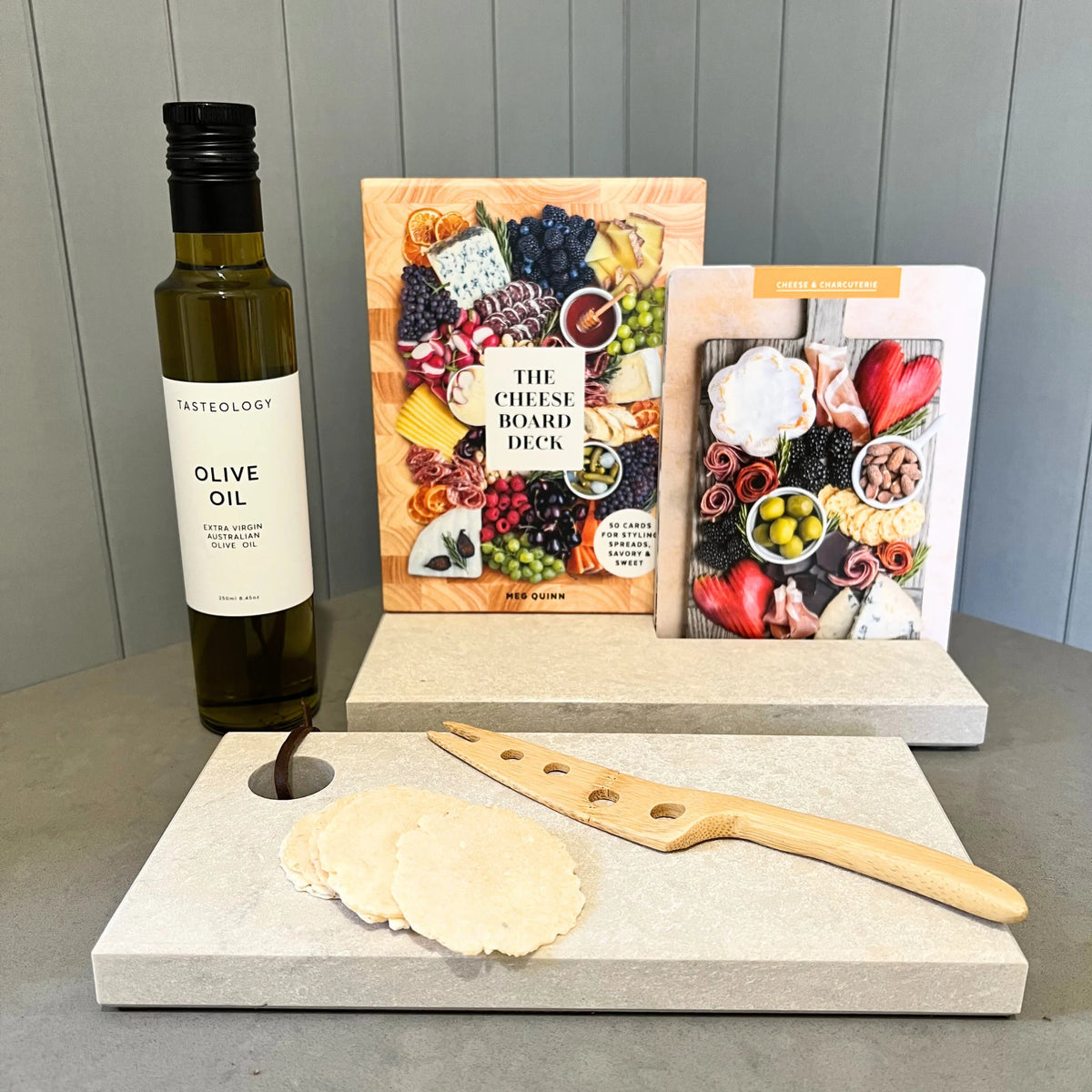 Keep calm and eat cheese. Gift box with Tasteology Olive Oil, The Cheese Board Deck by Meg Quinn, Condiment Stand and Prep Board from Caesarstone Calacatta Maximus with the look and feel of marble. Bamboo cheese knife with fork end.