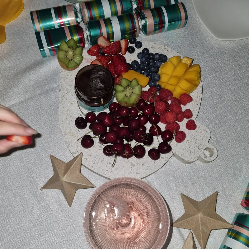 Christmas Decoration Shaped fruit platter with chocolate fondue on a festive table setting.