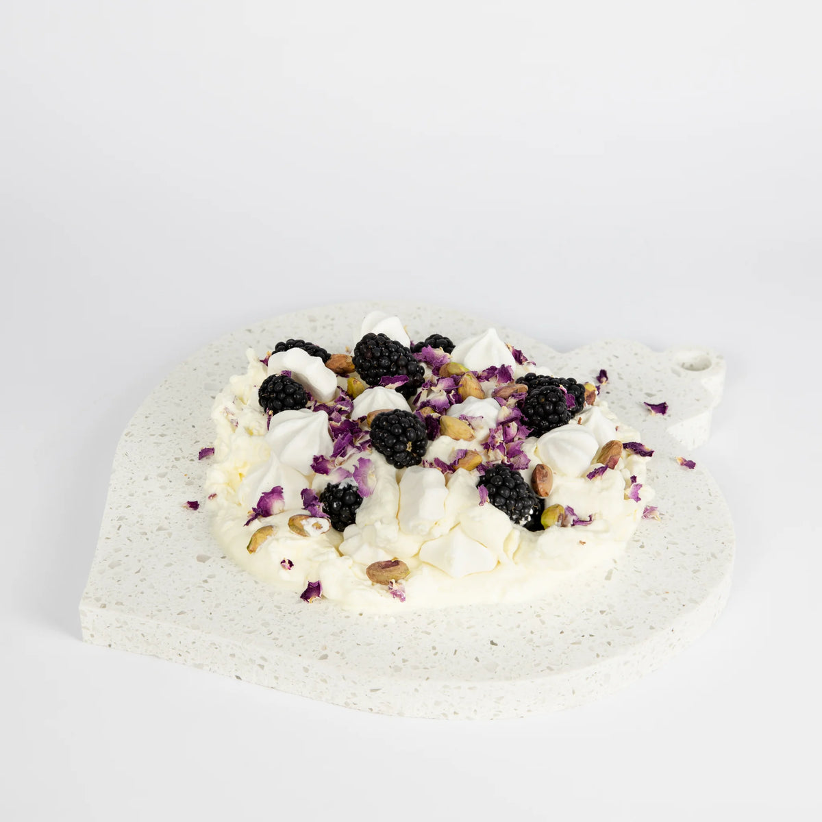 Teardrop ornament-shaped dessert platter with blackberries and cream on a light gray background