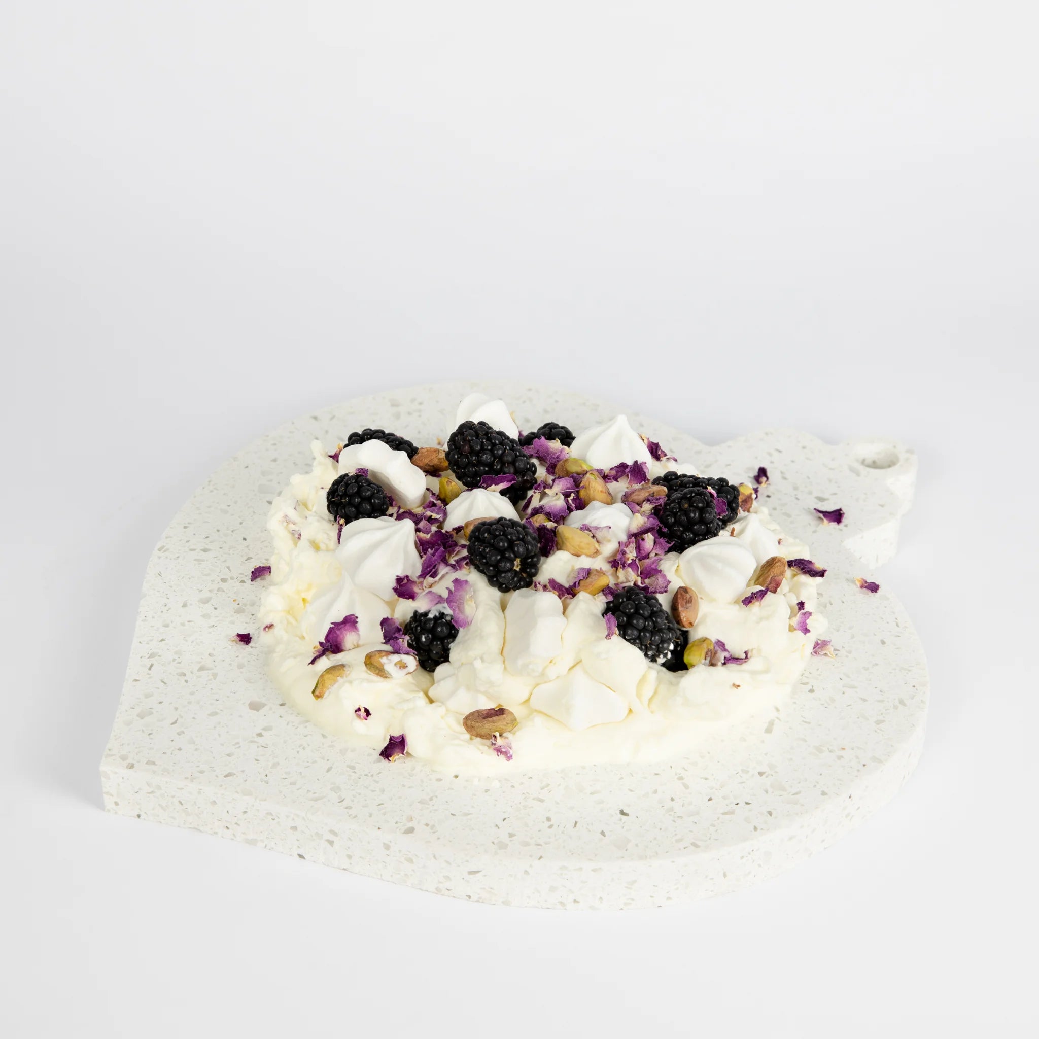 Teardrop ornament-shaped dessert platter with blackberries and cream on a light gray background
