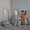 Two DStill Pilsner Beer Glasses on a grey surface, Aureliia Collection Arch Coasters in Caesarstone Rugged Concrete with a Byron Beef Jerky package in the background.