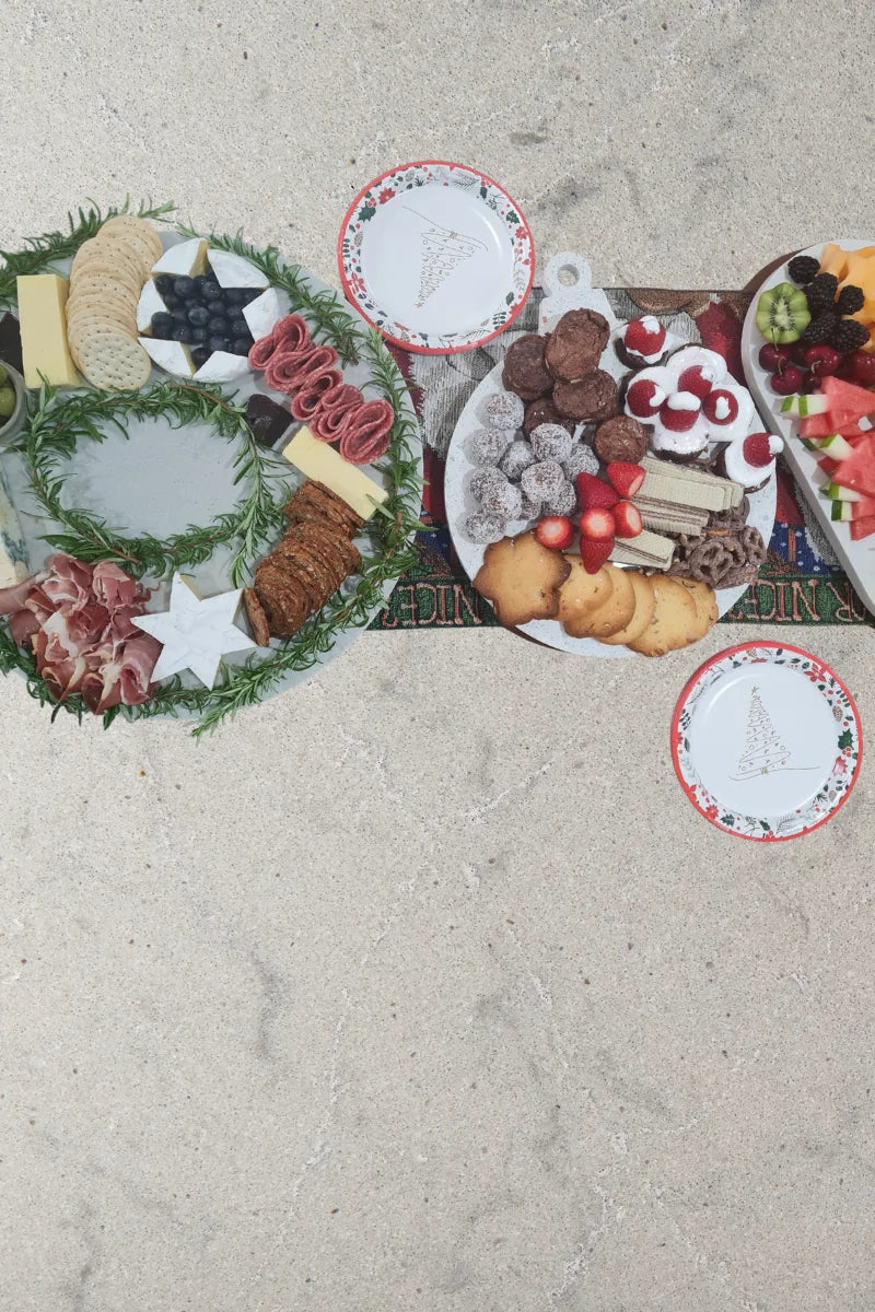 Festive charcuterie board in wreath shape with rosemary, crackers, cheese and cured meats on marble-look platter.