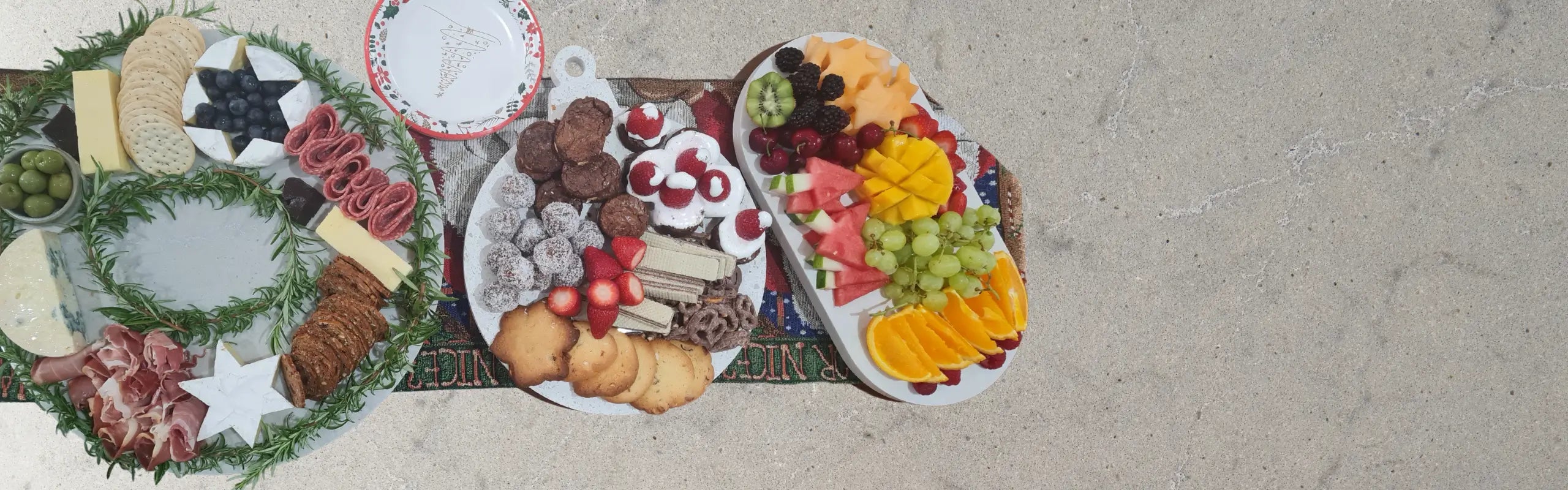 Christmas grazing platter with fruit, sweets and cheese displayed on Aureliia Collection serving boards.