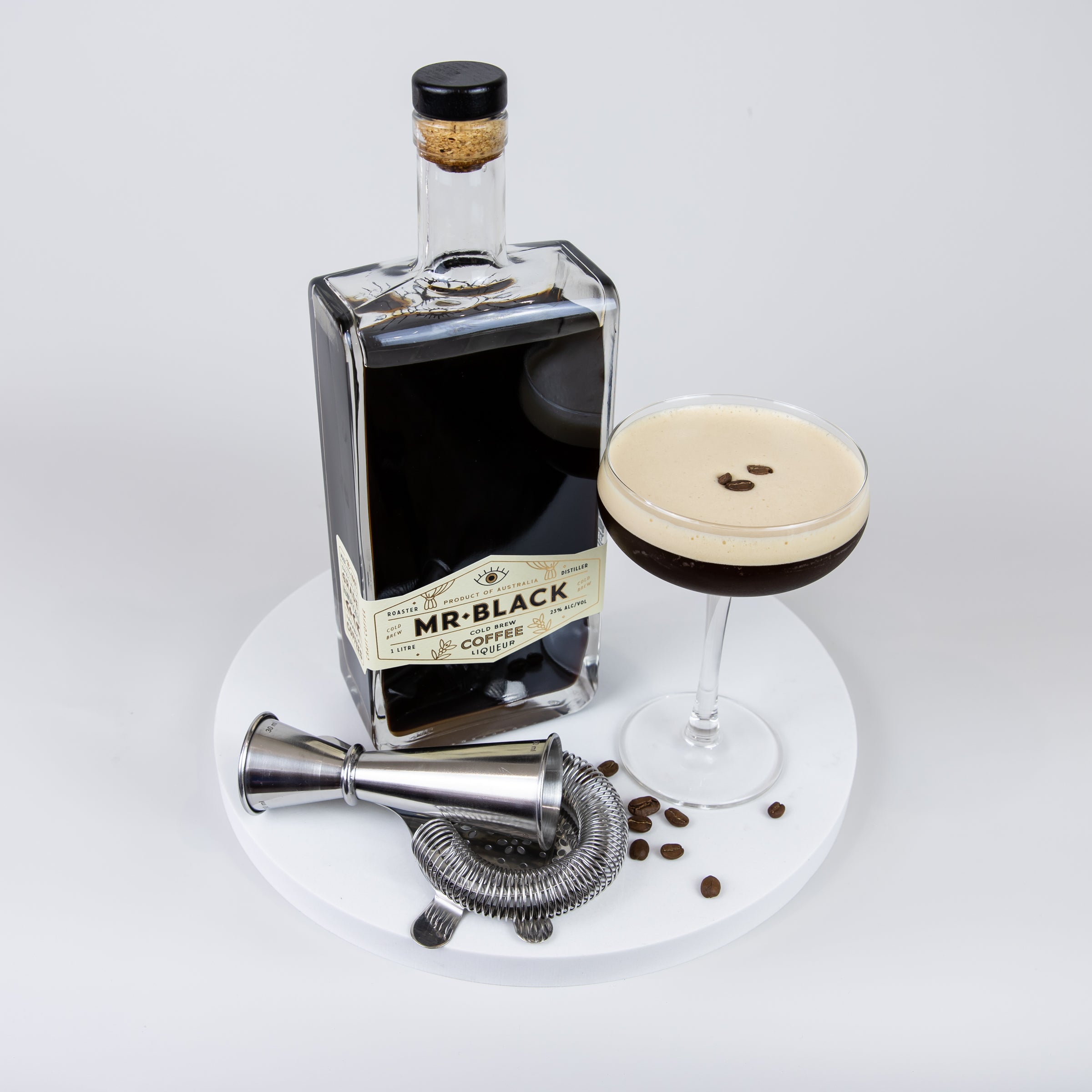 Large Quartz Round Serving Platter in Caeserstone Aterra Blanca by Aureliia Collection. This serving 30cm round platter is styled with espresso martini Mr Black Coffee Liquor and cocktail utensils.  An excellent home decor addition for the avid entertainer. Gift ideas for someone who has everything.