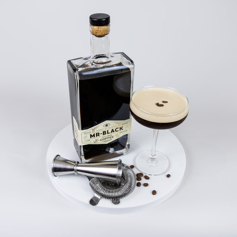 Large Quartz Round Serving Platter in Caeserstone Aterra Blanca by Aureliia Collection. This serving 30cm round platter is styled with espresso martini Mr Black Coffee Liquor and cocktail utensils.  An excellent home decor addition for the avid entertainer. Gift ideas for someone who has everything.