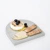 Arch quartz serving platter in Caesarstone Airy Concrete™ created by Aureliia Collection. Similar to a marble platter, the Arch Quartz cheese platter shown with baked camembert cheese topped with fresh blueberries, featuring Iris rattan gold cheese knife set. An excellent home decor gift for someone who has it all.