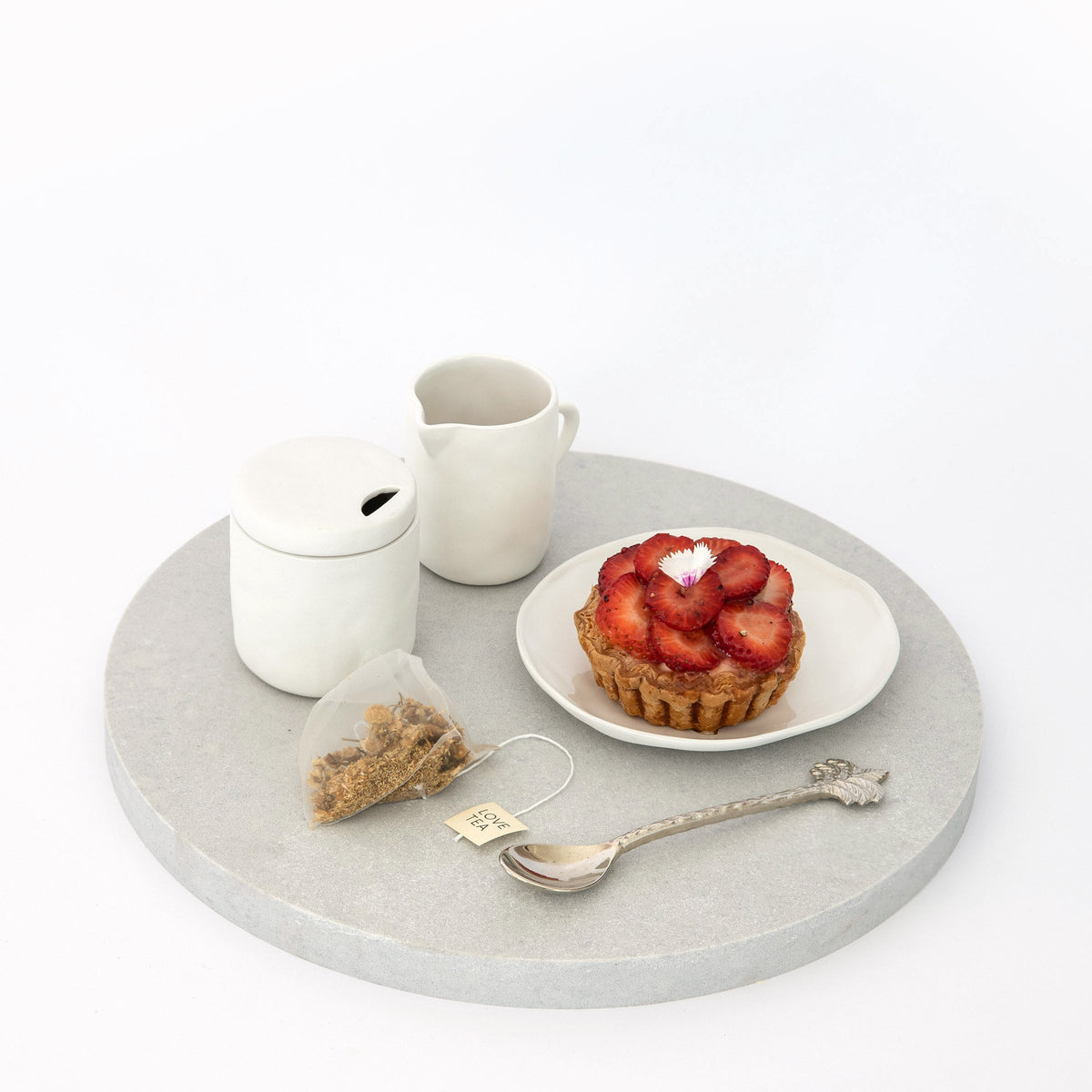 Large Quartz Round Serving Platter in Caeserstone Airy Concrete by Aureliia Collection. This serving 30cm round platter is styled with strawberry pastry tart and clay tea set.  An excellent home decor addition for the avid entertainer. Gift ideas for someone who has everything.
