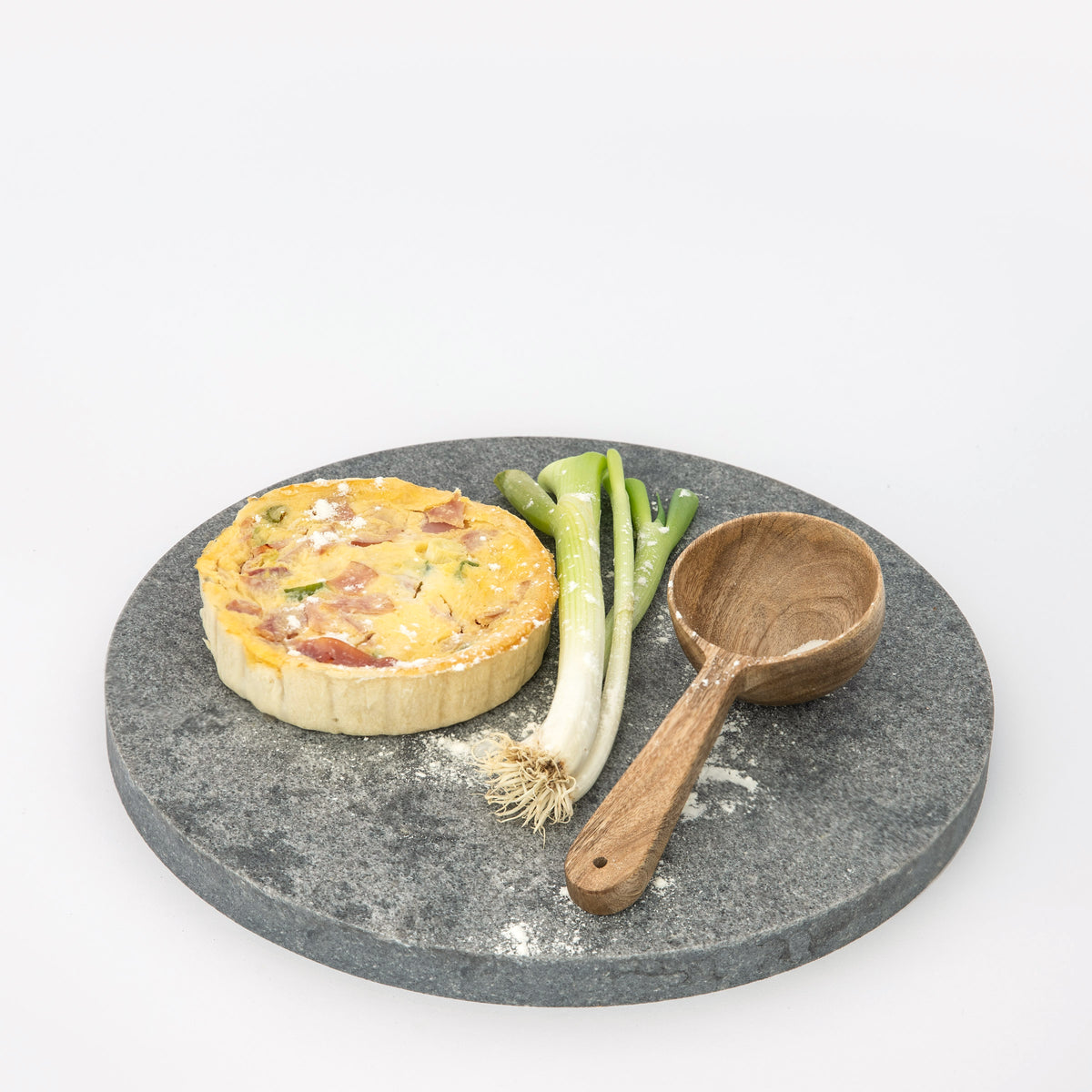Large Quartz Round Serving Platter in Caeserstone Rugged Concrete by Aureliia Collection. This serving platter is styled with timber soup spoon, fresh green onions and quiche. An excellent home decor addition for the avid entertainer.